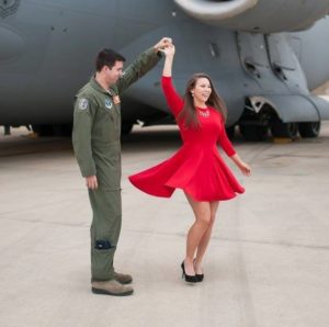 man in pilots jumpsuit twirling girl in red dress