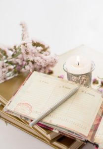 notebook, pen, candle, and flowers to indicate planning for wedding and first dance