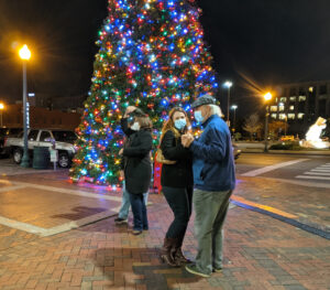 two couples dancing in front of Christmas tree
