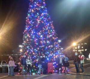 5 couples posed in front of christmas tree