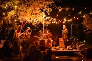 A band playing outside under twinkle lightss