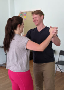 Man laughing while dancing with his fiance.