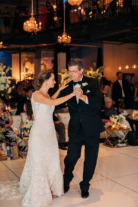 A father leading his daughter in promenade during their father-daughter dance.