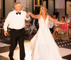 A father leading his daughter onto the floor for their father-daughter dance.