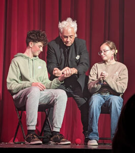 Two teenagers and a magician on stage.