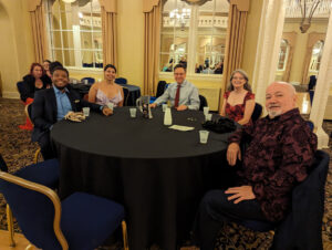 Participants in big band dance getaway dressed up and seated around a table.
